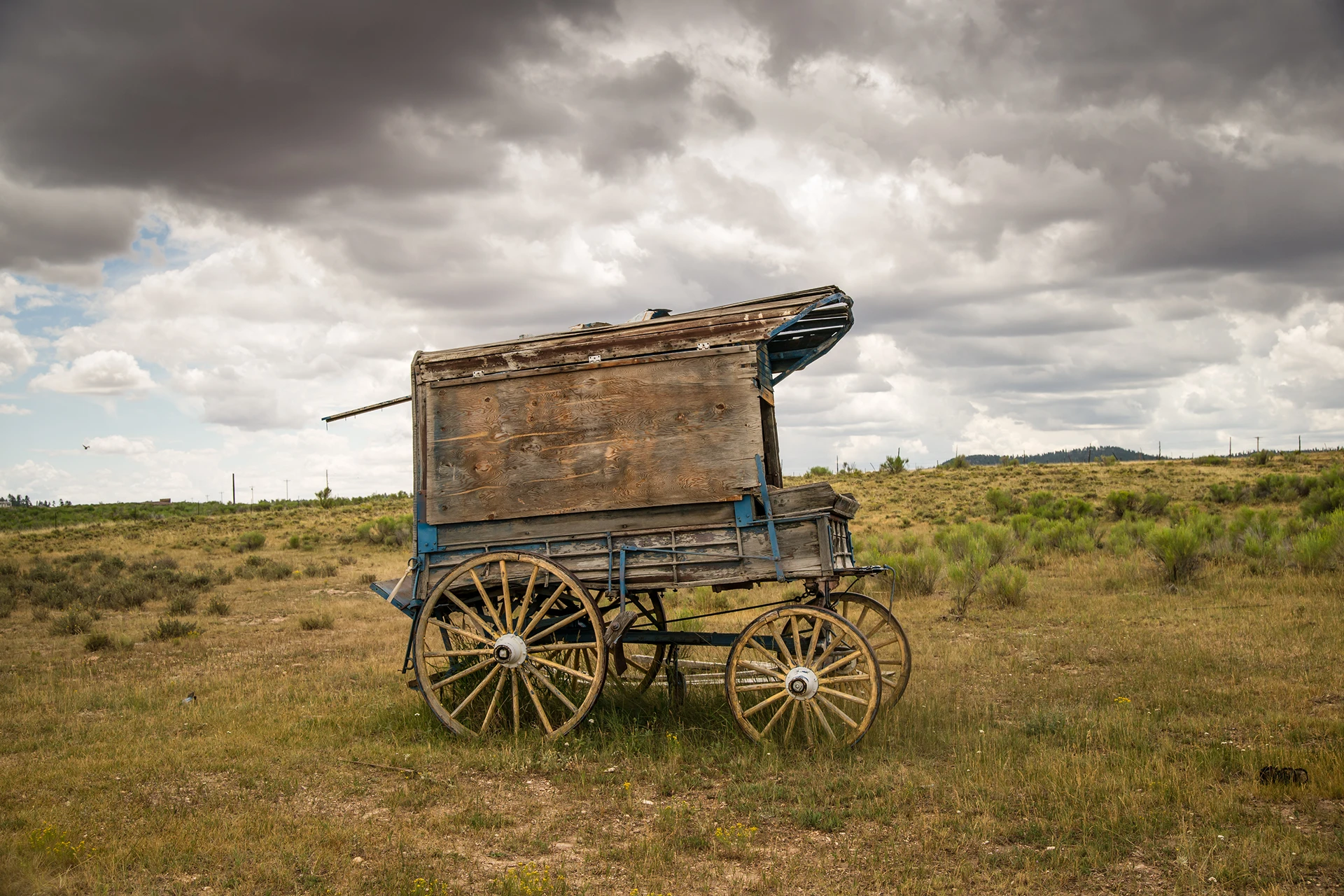 Old wooden wagon under cloudy sky.
